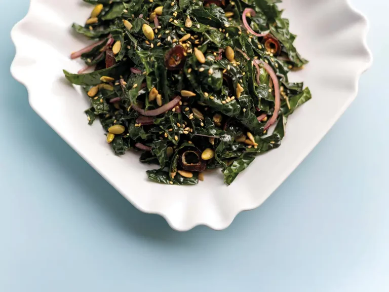 Kale salad in a square white serving bowl.
