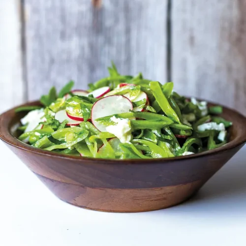 Walnut salad bowl containing Lágrimas Salad with Snap Peas, Radishes and Mint