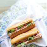 Two halves of a Bánh mì arranged on blue/white linens.
