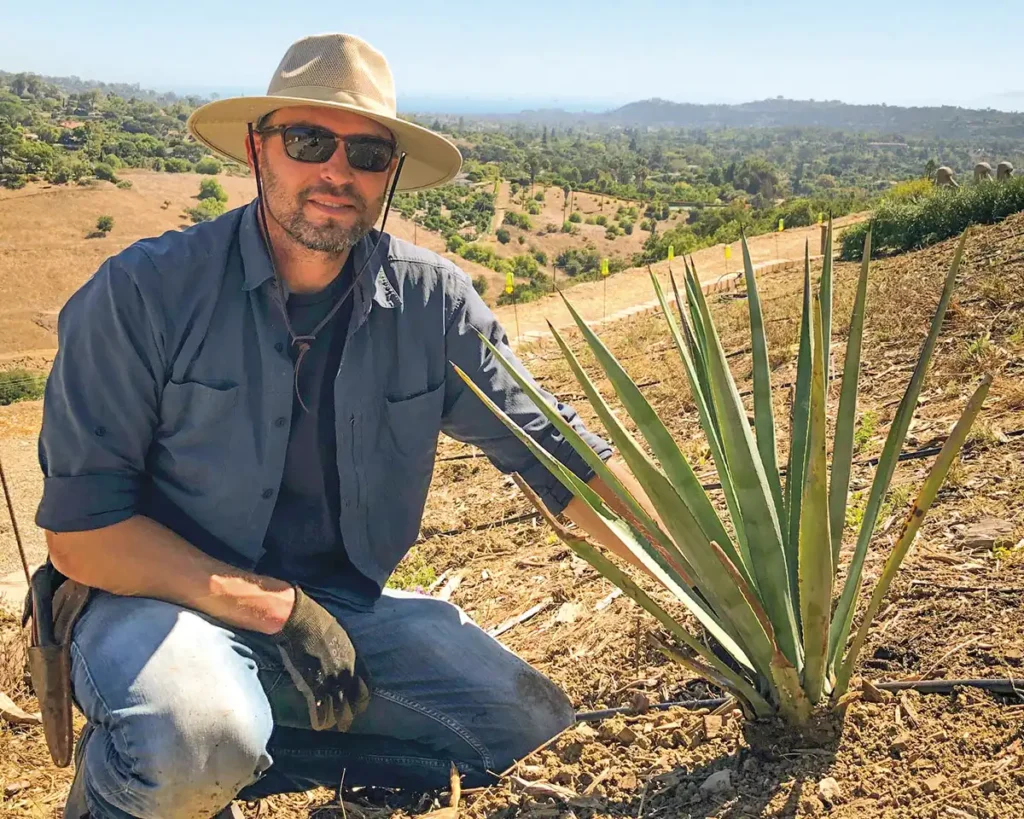 Ryan Carr crouches next to an Agave.