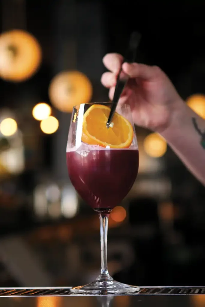 Bartender adding an orange wheel to a Lambrusco Spritz.
