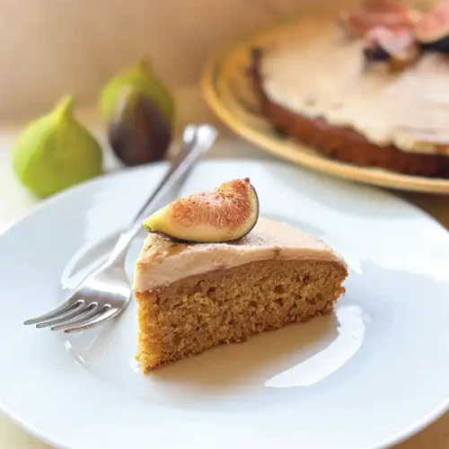 Taylor’s Blood Orange Olive Oil Cake with Fig Balsamic Mascarpone Frosting on a white plate with a fig on top.