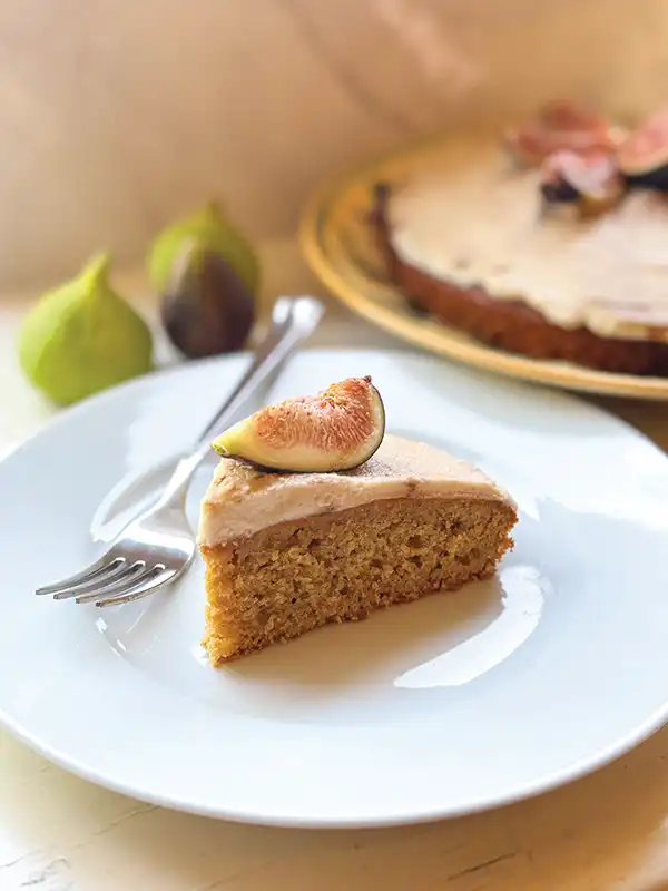 Taylor’s Blood Orange Olive Oil Cake with Fig Balsamic Mascarpone Frosting on a white plate with a fig on top.